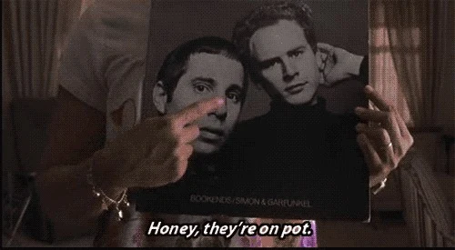 Fotograma de la película Almost Famous, dos hombres mirando una portada de disco de Simon & Garfunkel con el subtítulo "Honey, they're on pot"