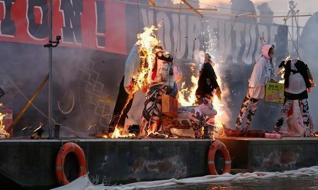 Efigies punk ardiendo sobre una balsa en el río Támesis, con salvavidas naranjos al frente